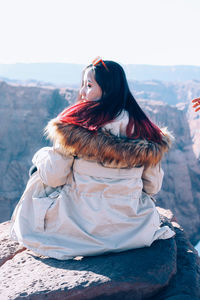 Portrait of young woman standing on mountain against sky