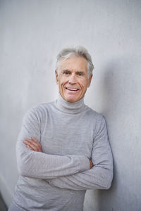 Elderly man leaning on gray wall