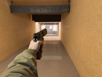 Cropped hand holding handgun in corridor