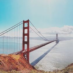 Suspension bridge over river against sky