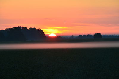 Scenic view of silhouette landscape against orange sky