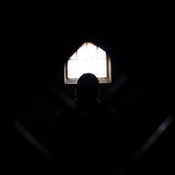 Rear view of silhouette man standing in window