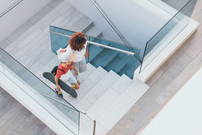 High angle view of boy with skateboard and woman on staircase 