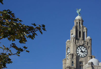 Low angle view of clock tower against blue sky