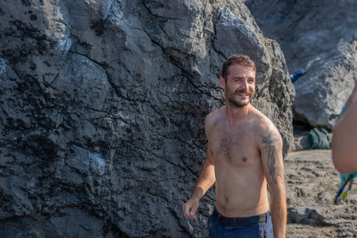 Portrait of young man standing in front of rock, bouldering.