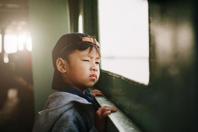 Boy looking away through window in train