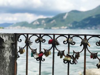 Close-up of padlocks on railing against cloudy sky