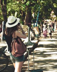 Rear view of woman using mobile phone in park