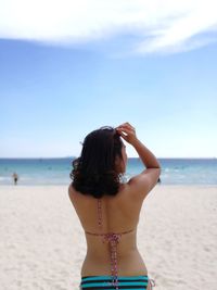 Rear view of woman standing on beach against sky