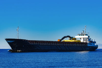 Ship sailing in sea against clear blue sky