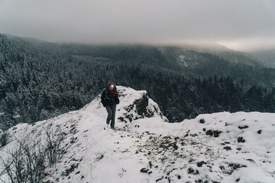 Rear view of person on snowcapped mountain against sky