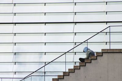 Low angle view of man sitting in stairs in front of an office building