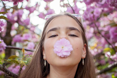 Close-up of young woman blowing flowers