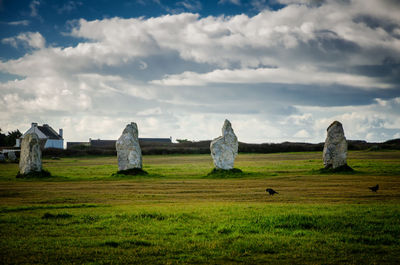 Hay bales on field against cloudy sky