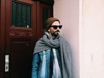 Man smoking cigarette while standing against house