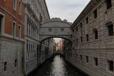 Bridge of sighs amidst building over canal against sky