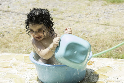 Happy girl playing in bucket with water