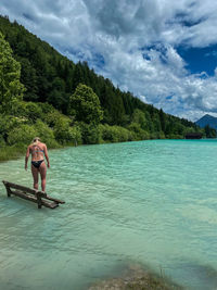 Young lady on a bench in alpine lake walchensee against mountain and sky