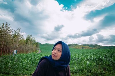 Portrait of beautiful young woman lying on land against sky