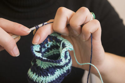 Cropped image of woman knitting booties at home