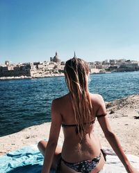 Rear view of woman in bikini by sea