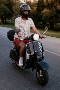 Young handsome male with hipster outfit rides a black vintage motorbike. he is a caucasian male   