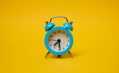 Close-up of alarm clock against yellow background