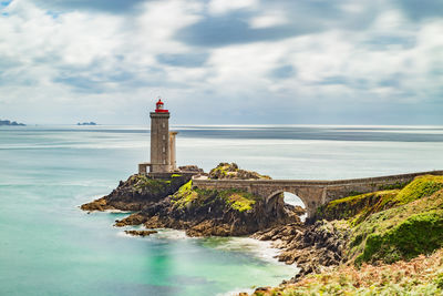 Lighthouse by sea against sky
