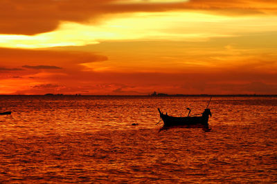 Silhouette boat in sea against orange sky