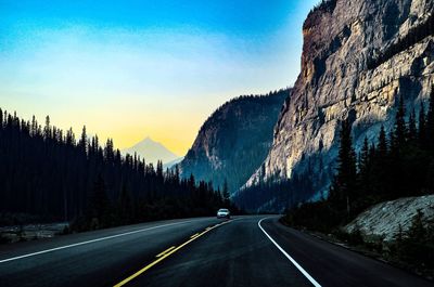 Road by mountains against sky