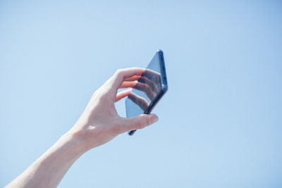 Cropped image of woman holding mobile phone park