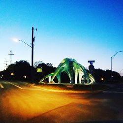 Illuminated road against blue sky at night