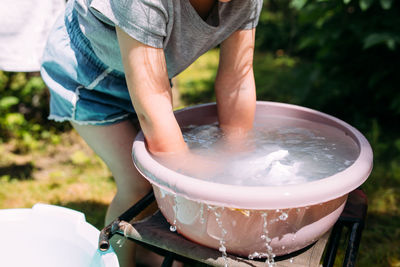 Little preschool girl helps with laundry. child washes clothes in garden