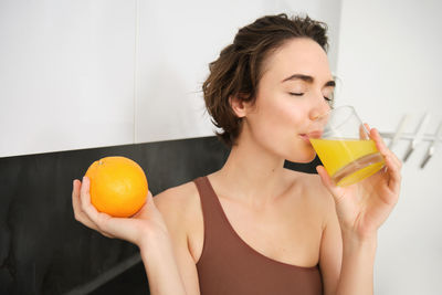 Young woman holding drink at home