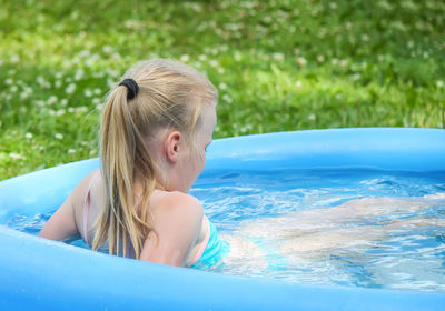 Girl sitting in wading pool at lawn