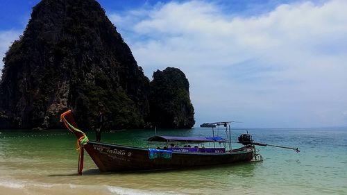 Boat moored on sea shore against sky