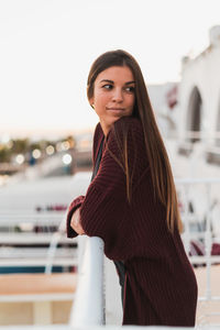 Side view of thoughtful woman standing at railing against clear sky