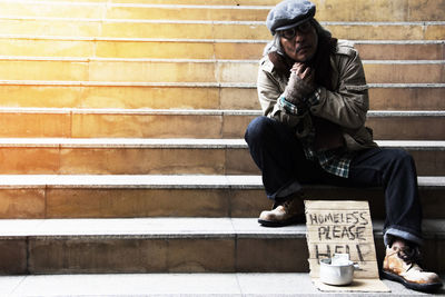 Beggar with placard sitting on steps in city