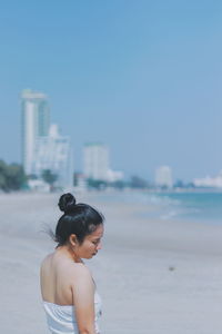 Woman standing at beach against clear blue sky