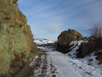 Road amidst snow covered mountains against sky