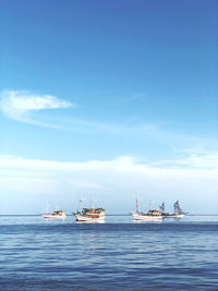 Sailboats on sea against blue sky