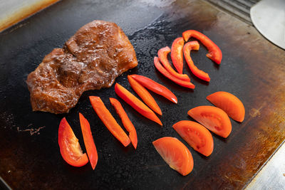 Close-up cook fries on a large professional stove a large pickled piece of meat and pepper. 