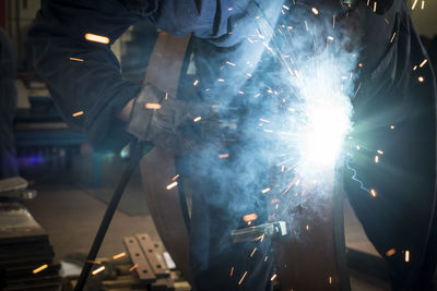 Midsection of man welding at factory