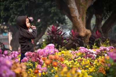 Side view of woman standing by flowering plants