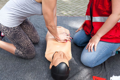 Midsection of paramedics performing cpr on dummy