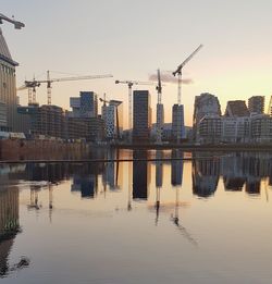 Modern buildings by river against clear sky