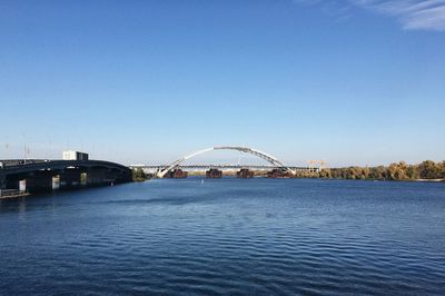 Bridge over calm river against clear sky
