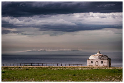 Church by sea against dramatic sky