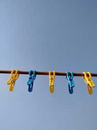 Low angle view of clothespins hanging on clothesline against sky