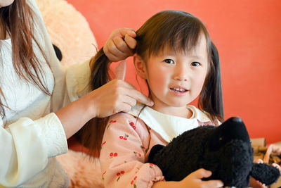 Mother combing daughter hair at home